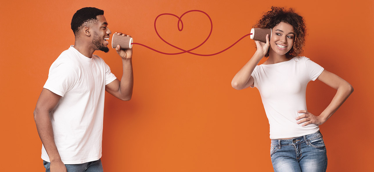 Cute couple talking with can phones, cord in heart shape