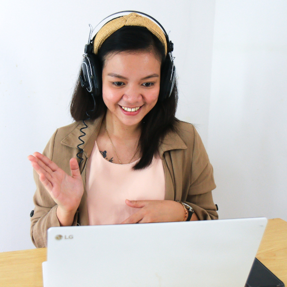 Asian young woman at computer, smiling and waving